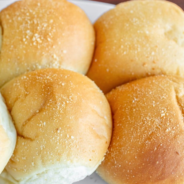 Close-up of several golden-brown Filipino pandesal rolls, lightly dusted with breadcrumbs.