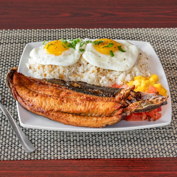 Filipino fried bangus (milkfish) with garlic rice, two fried eggs, and diced tomatoes and mangoes.