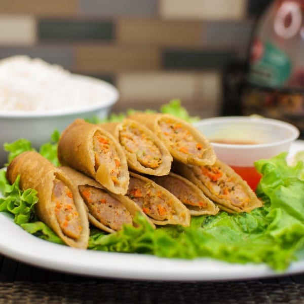 Filipino lumpia spring rolls, cut in half, served on lettuce with rice and dipping sauce.