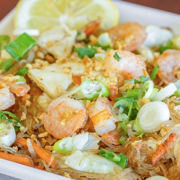Close-up of Fil Cuisine's Pancit Bihon with shrimp, vegetables, and a lemon wedge.